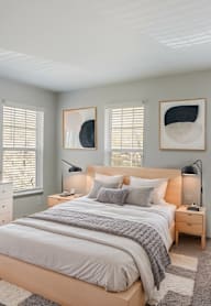 A bedroom with a bed, a lamp, and a painting on the wall.