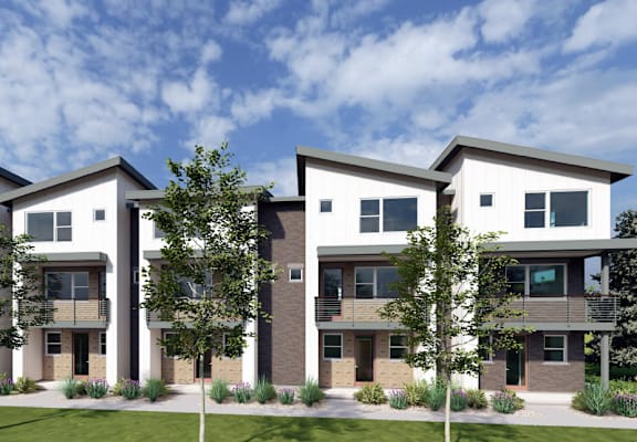 A modern three-story residential building with a green lawn in front.