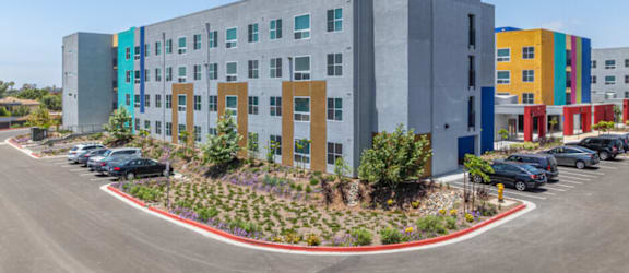 A modern multi-story building with a parking lot in front.