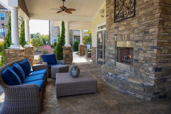 a covered patio with a fireplace and wicker furniture