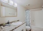 Thumbnail 4 of 20 - A bathroom with a sink, mirror, toilet, and shower.