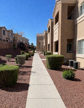 A long concrete walkway separates apartment buildings.