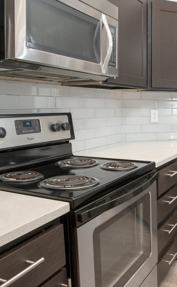 an updated kitchen with stainless steel appliances and white counter tops