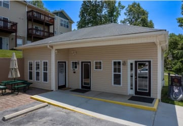 a tan building with two doors and a table and chairs in front of it