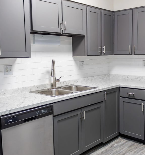 A kitchen with a sink, stove, and cabinets.