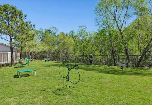 A park with a green lawn and a metal sculpture.
