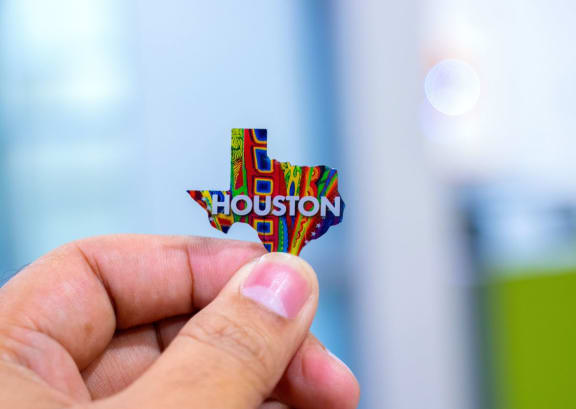 hand holding a Texas shaped sign with Houston writtin inside it
