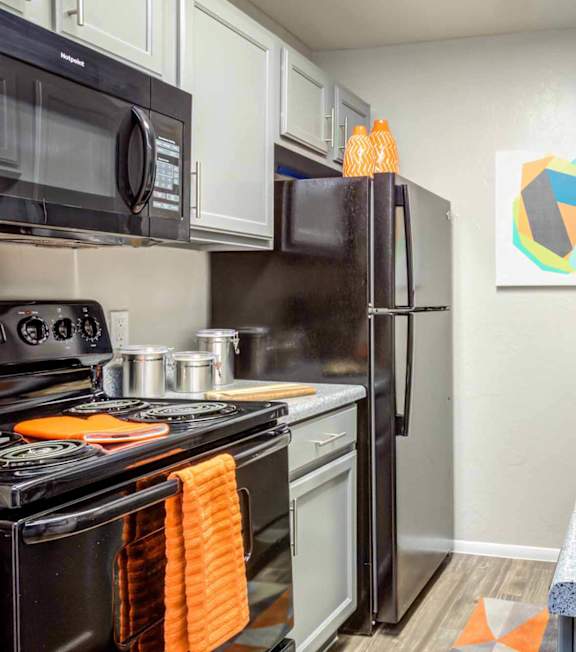 A kitchen with black appliances and a grey countertop.