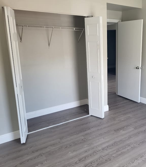 A room with a white closet and grey flooring.