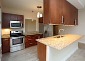 Thumbnail 27 of 31 - A kitchen with a granite countertop and stainless steel appliances.
