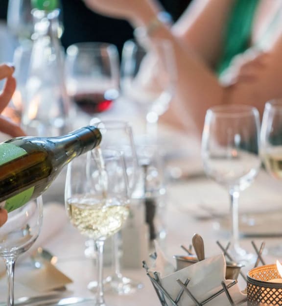 a person pouring wine into a glass on a table  at Icon Apartment Homes at Ferguson Farm, Bozeman, Montana