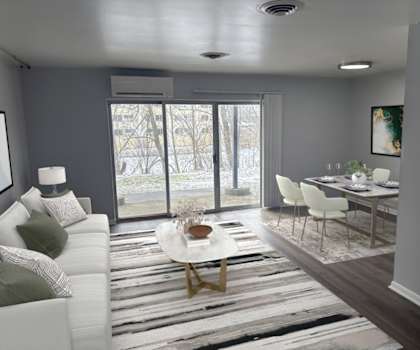 A modern living room with a white sofa, a coffee table, and a dining table set up.