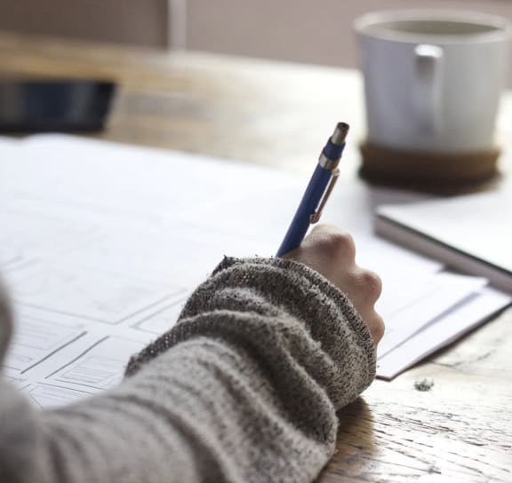a person writing on a piece of paper with a pen
