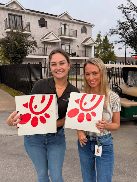 Two women holding red and white paper with a design on it.
