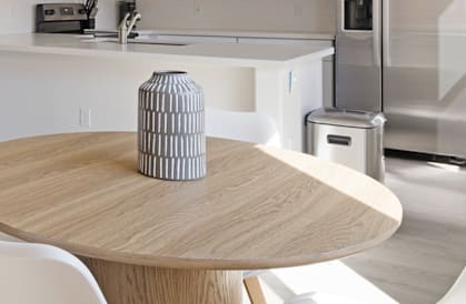 A kitchen with a wooden table and white chairs.