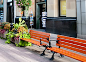 Thumbnail 2 of 4 - A brown bench is in front of a building with a sign that says "Stanley".