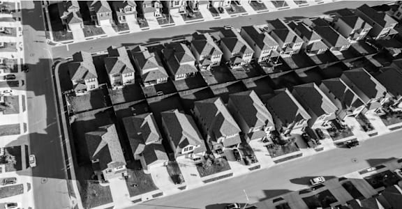 A black and white aerial view of a city street with buildings on either side.