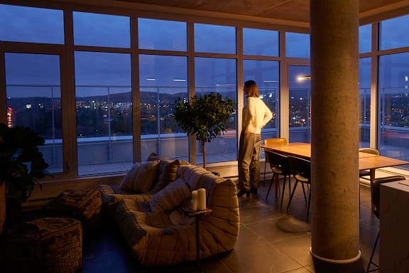 A woman stands in a room with a view of the city at night. at Le Columbia Apartments , Gatineau, J8Y 0A8