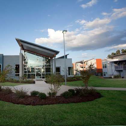 A modern building with a glass entrance and a landscaped front yard.