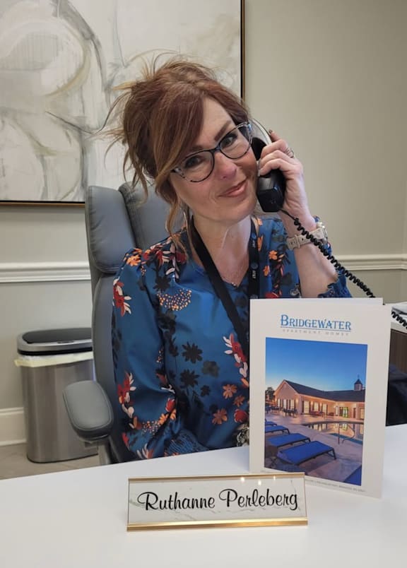 A woman in a floral shirt is talking on the phone and holding a booklet titled "Bridgewater".