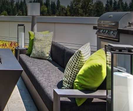 A patio with grey couches and green pillows.