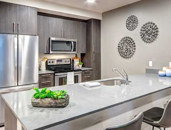 Modern kitchen with a stone tray of greens on the island at Upton Flats Apartments, Seattle, Washington