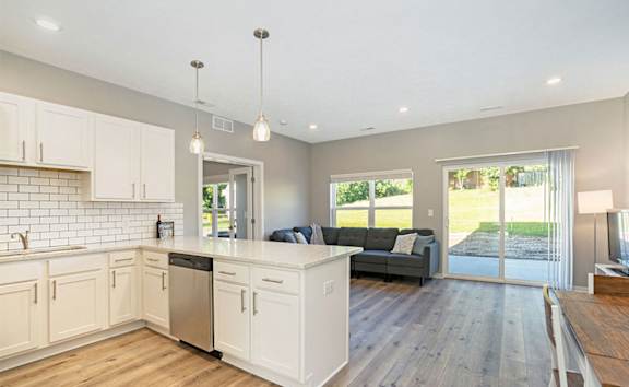 A kitchen with wooden floors and white cabinets.
