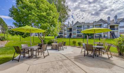 A patio with tables and chairs and umbrellas.