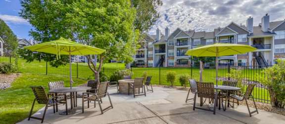 A patio with tables and chairs and umbrellas.