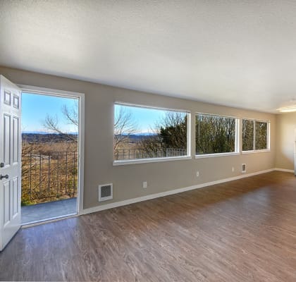an empty living room with a kitchen and a large window