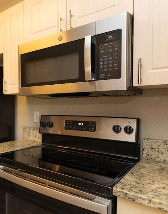 A kitchen with a stove, microwave, and refrigerator.