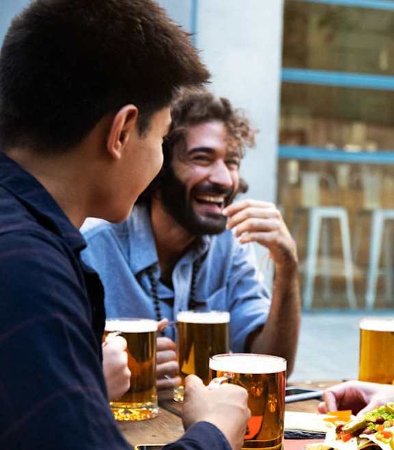 Three people are sitting at a bar, enjoying drinks and conversation.