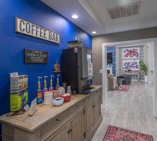 A coffee bar with a blue wall and a wooden counter.
