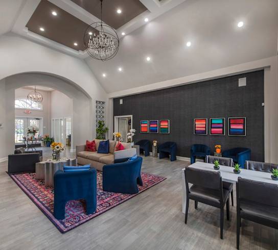 A spacious living room with a blue rug and a dining table set up.
