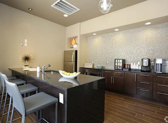A modern kitchen with a black countertop and grey bar stools.