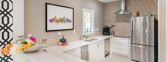 A modern kitchen with a white countertop and a fridge on the right.