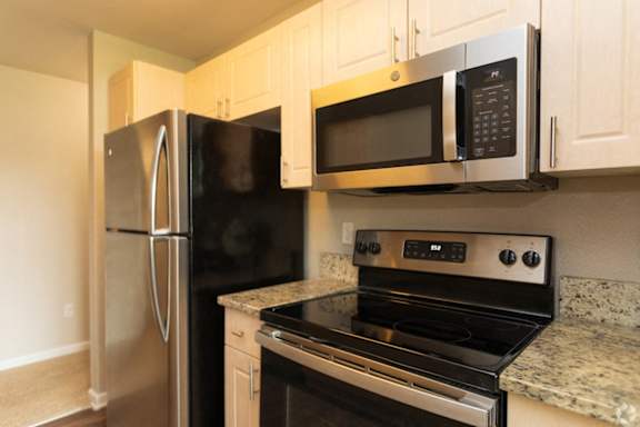 A kitchen with a stove, microwave, and refrigerator.