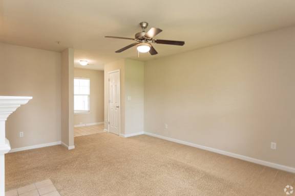 A room with a ceiling fan and carpeted floor.