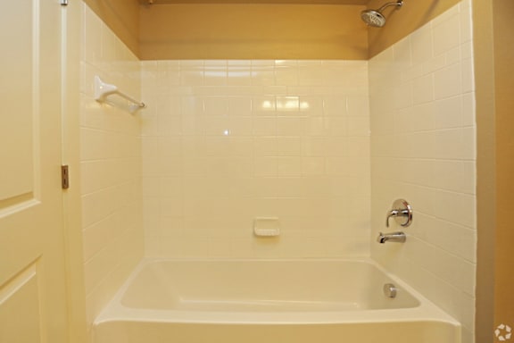 A white bathtub in a bathroom with yellow walls.