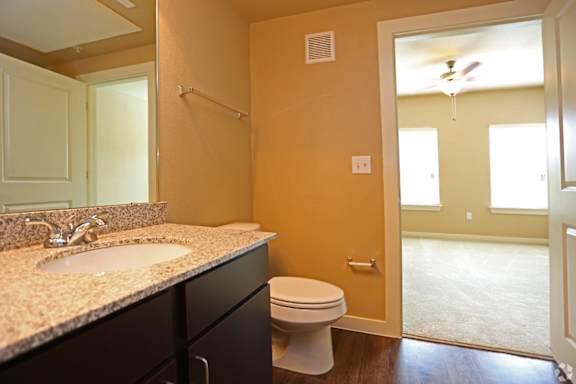 A bathroom with a toilet, sink, and mirror.