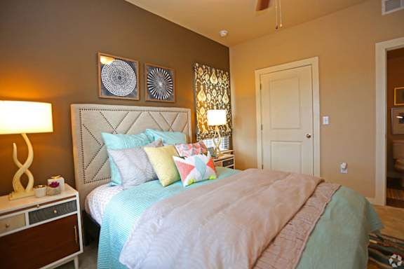 A bedroom with a bed, nightstand, and wall art.
