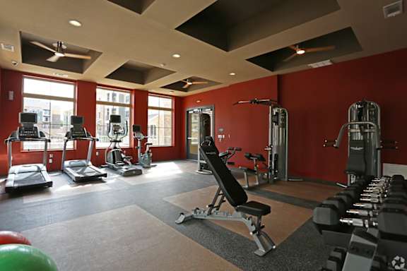 A gym with a variety of equipment including treadmills, weights, and exercise machines.