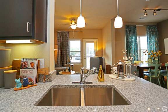 A kitchen with a granite countertop and a stainless steel sink.