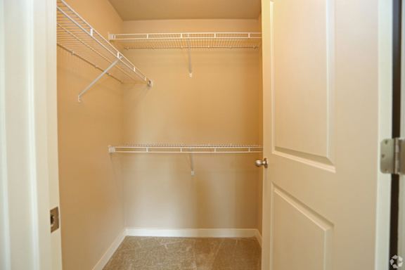 Empty walk-in closet with white shelves and a white door.
