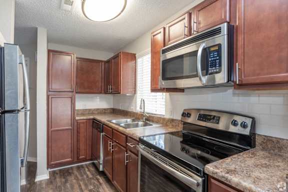 A kitchen with brown cabinets and a black stove top oven.