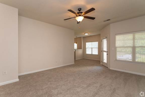A spacious room with a ceiling fan and carpeted floor.