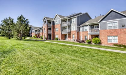 A row of modern brick apartment buildings with green lawns in front.