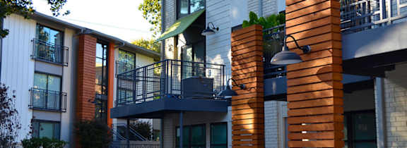 A modern building with a balcony and a small garden.