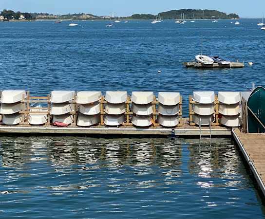 a row of chairs sitting on top of a wooden pier next to a body of water at Highlands at Faxon Woods, Quincy, MA
