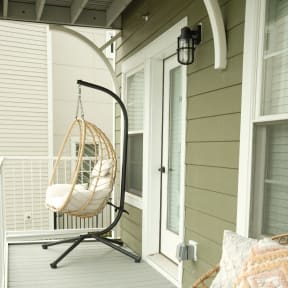 a porch swing with a pillow on it and a bench on the porch